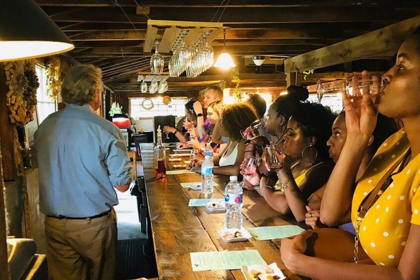 A group of people sitting at a wooden table in a rustic setting, with a barista serving coffee. 5