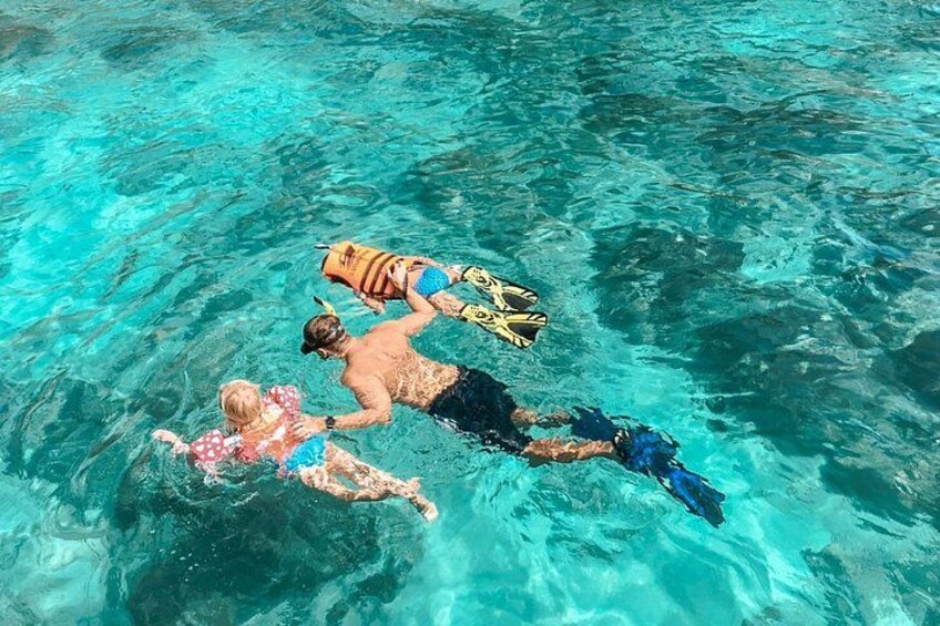 Three people swimming in clear blue water. 1