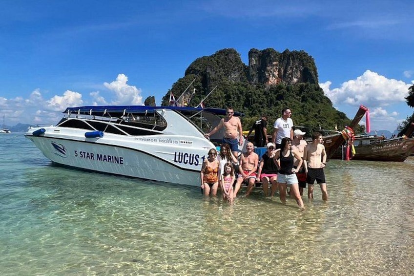 Un gruppo di persone vicino a una barca chiamata '5 Star Marine', con un'isola rocciosa sullo sfondo. 1