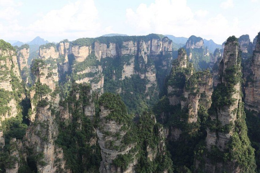 Een bergachtig landschap met torenhoge rotsformaties en een dicht bos. 1