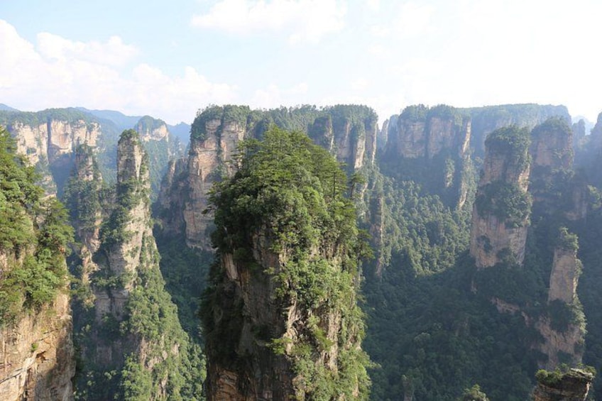 Een bergachtig landschap met torenhoge rotsformaties en weelderige groene begroeiing. 5