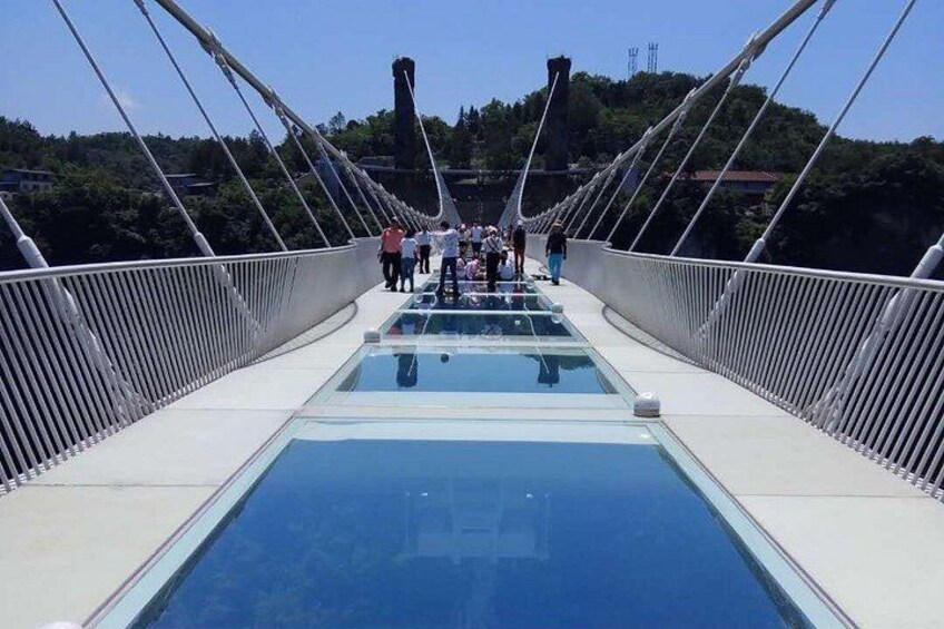 Eine Fußgängerbrücke mit Glasverkleidungen und Personen, die daraufgehen. 3