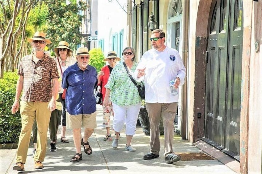 Un grupo de personas caminando por una acera en un área urbana con edificios y árboles. 3