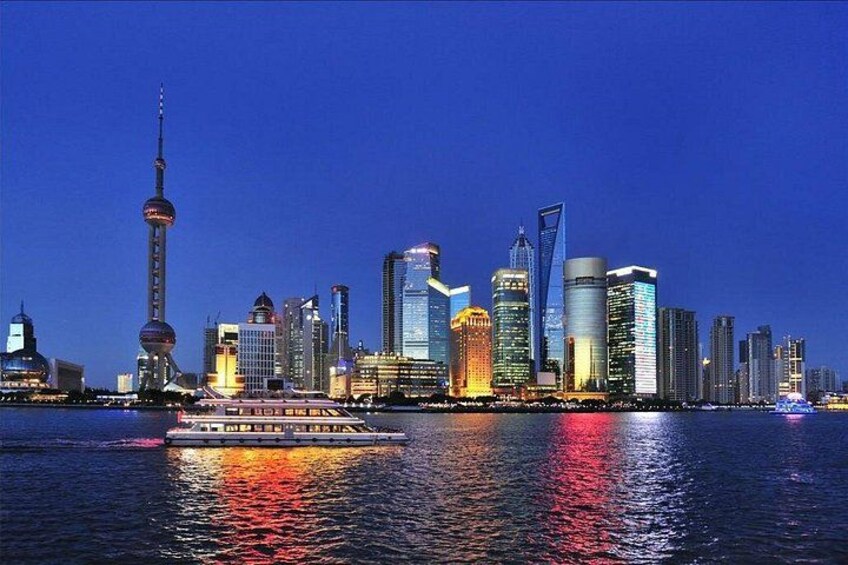 A city skyline with illuminated buildings and a riverboat in the foreground. 4