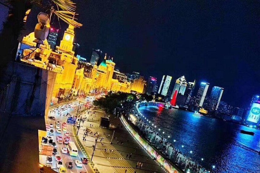 A nighttime cityscape with illuminated buildings, a waterfront promenade, and a large, brightly lit structure resembling a temple or mosque. 3
