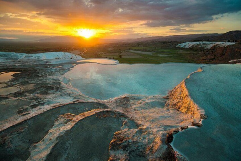 Un coucher de soleil sur une zone géothermique, avec des bassins d’eau minérale et une vue lointaine sur l’horizon. 2