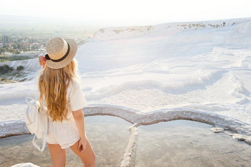 A person standing on a concrete platform overlooking a vast salt flat with a distant town visible in the background. 5
