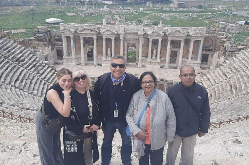 A group of people standing in front of an ancient amphitheater with ruins and columns. 2