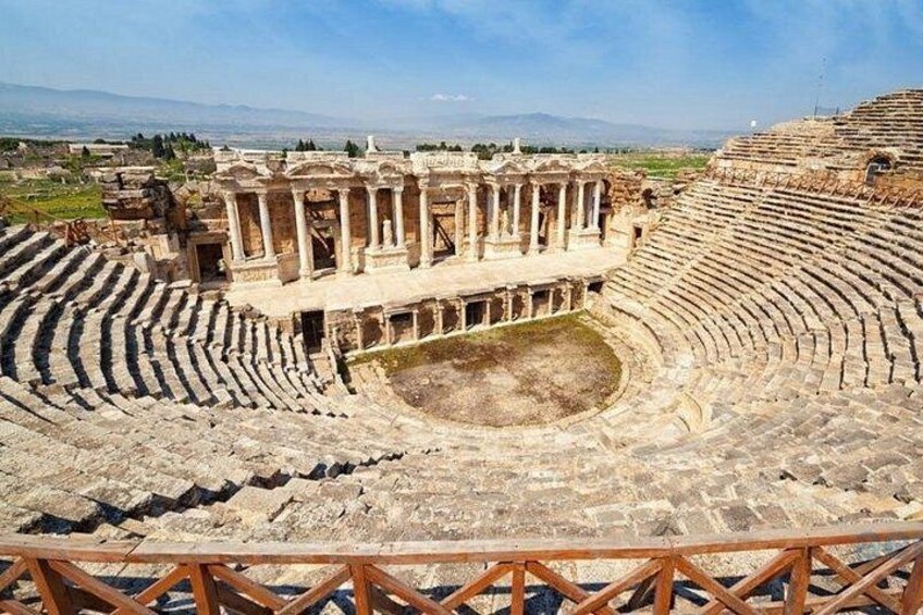 An ancient amphitheater with stone seating and a central stage. 3