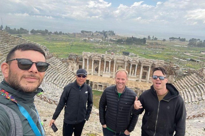 A group of people standing in front of an ancient amphitheater with ruins. 4
