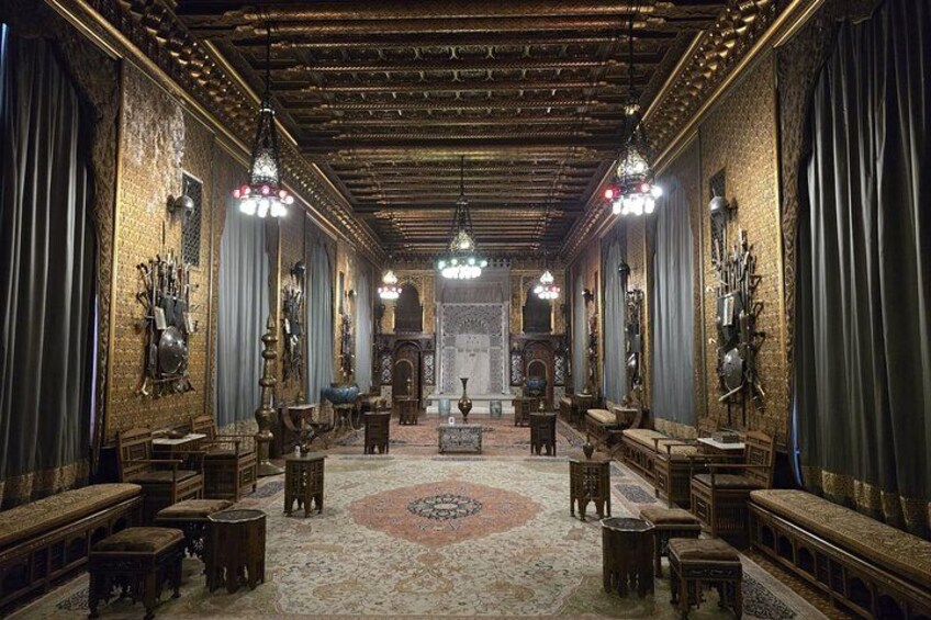 An ornate room with a patterned carpet, wooden furniture, and decorative wall hangings. 3