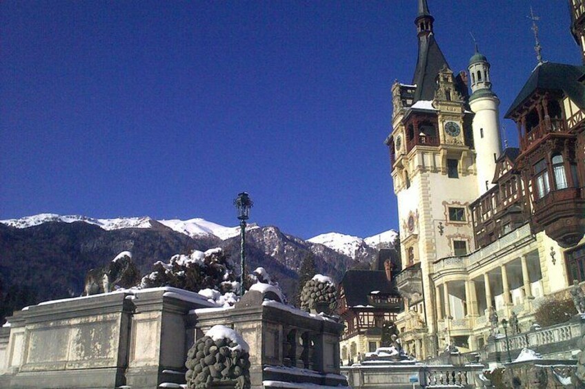 A snow-covered mountain range, a historic building with ornate architecture, and a statue in the foreground. 4