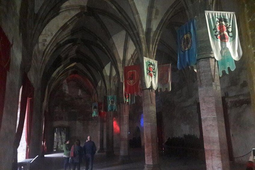 A cathedral interior with arched ceilings, stone columns, and flags. 4