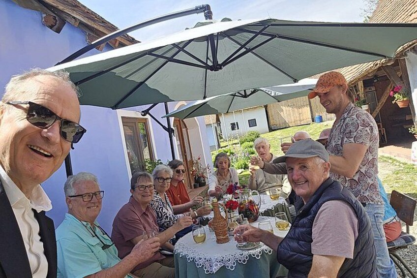 A group of people sitting around a table with drinks, under a large umbrella. 2