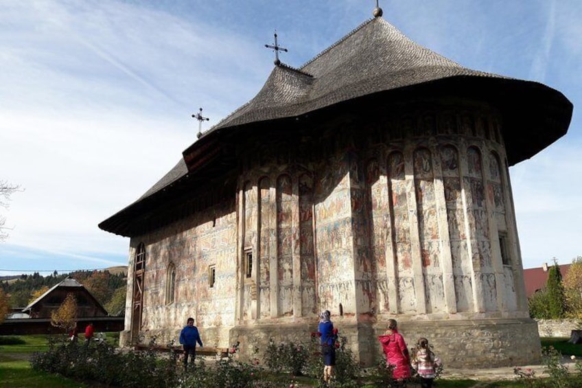 Un bâtiment historique doté d’un toit en forme de dôme surmonté d’une croix, entouré de verdure. 1