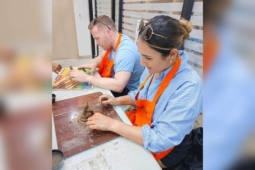 Dos personas trabajando sobre una superficie de madera, posiblemente tallando o armando algo. 2