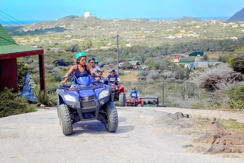 Un groupe de personnes circulant en quads sur une route, avec un paysage rural en arrière-plan. 4