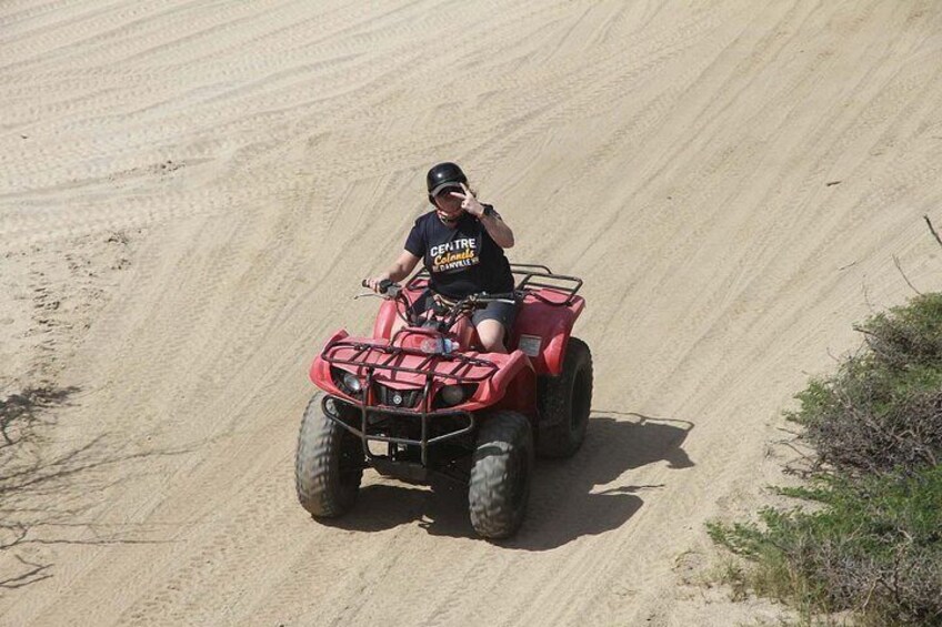 A person riding a red ATV on a sandy trail. 3