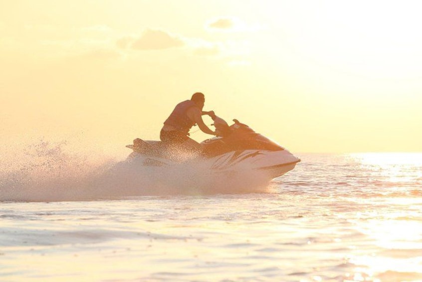 A person riding a jet ski on water during sunset. 2