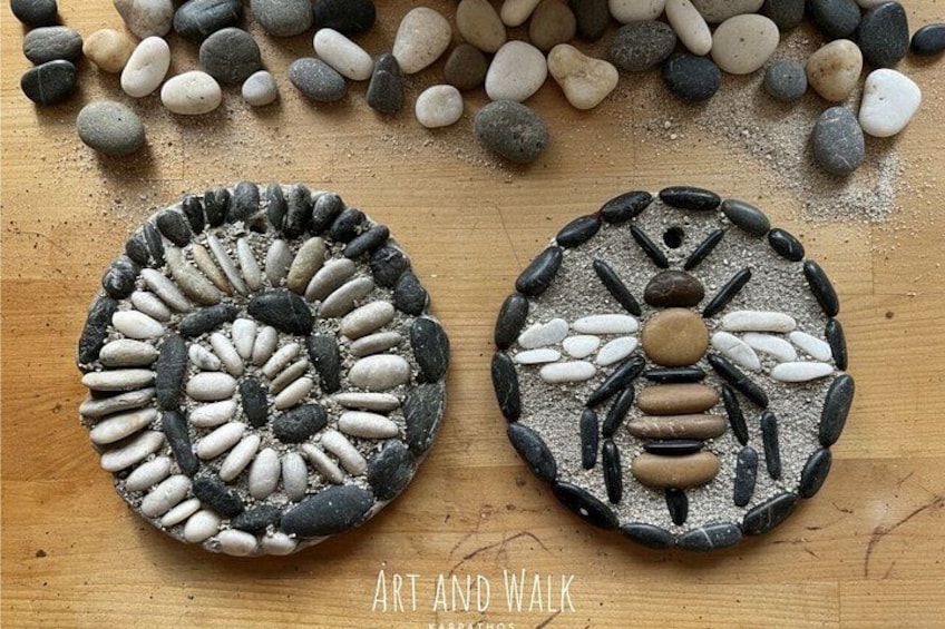 Two circular stone art pieces on a wooden surface, surrounded by scattered stones. 1