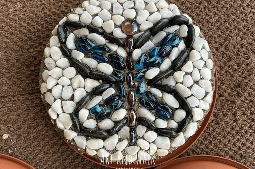 A decorative arrangement of white and black pebbles in a circular pattern with a central blue glass piece. 5