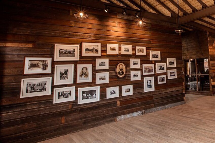 Eine Wand mit gerahmten Fotografien und einem zentralen Porträt. 4