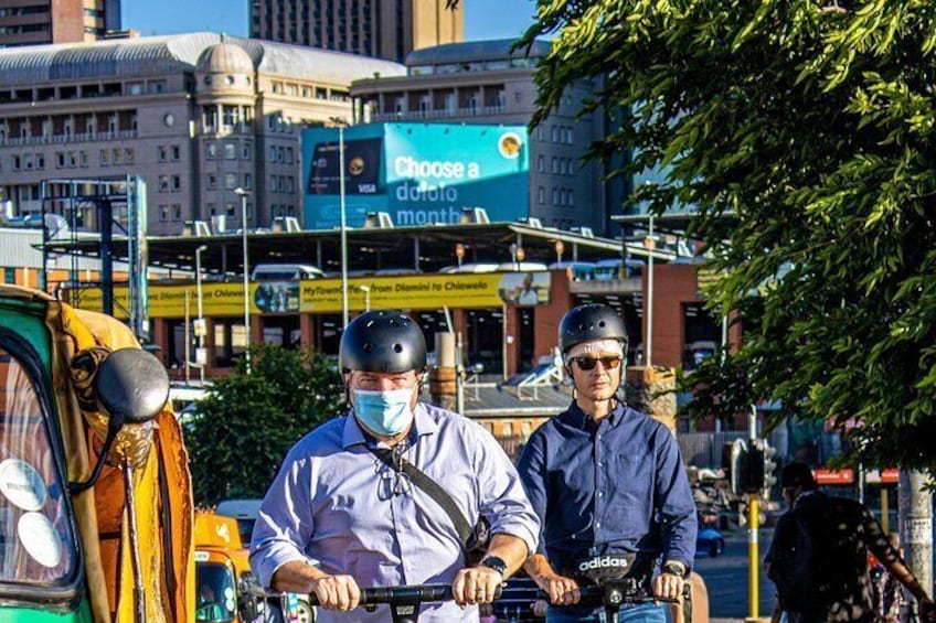 Two people on a motorcycle, a yellow taxi, and a building with a billboard. 5