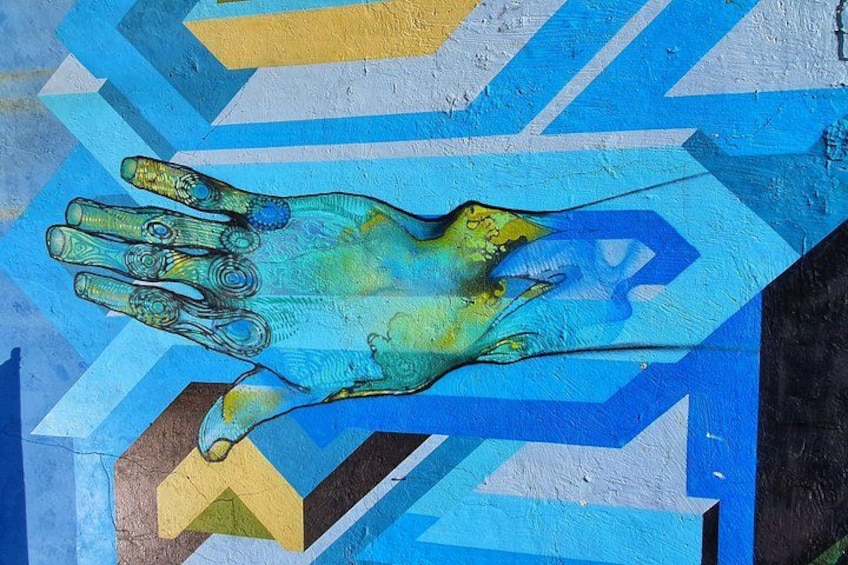 A hand-painted mural with geometric patterns and a hand reaching out. 5