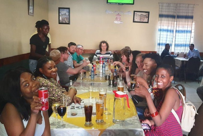 Un grupo de personas sentadas alrededor de una mesa con bebidas y una pantalla de televisión. 4