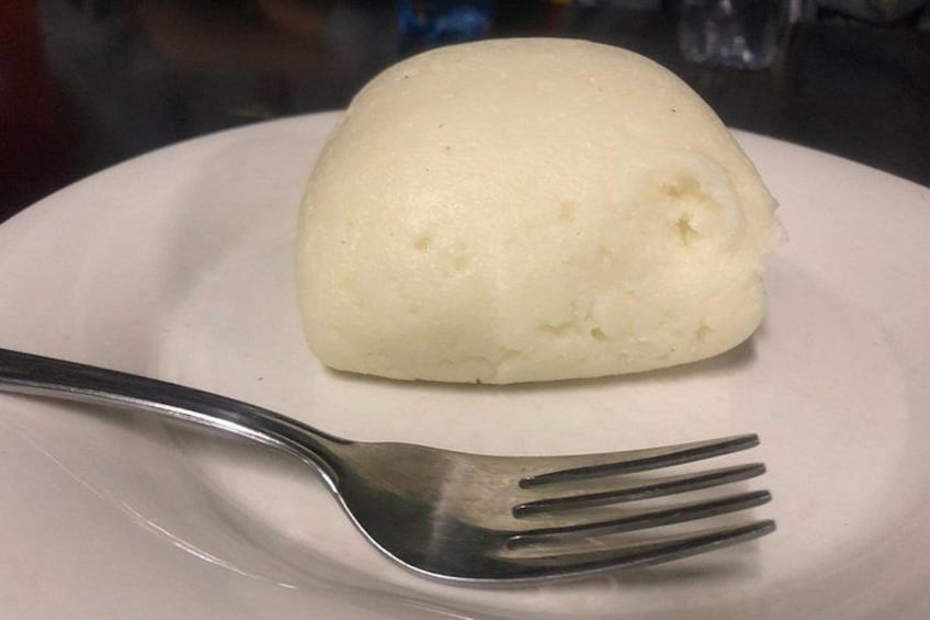A white dumpling on a white plate with a fork beside it. 4