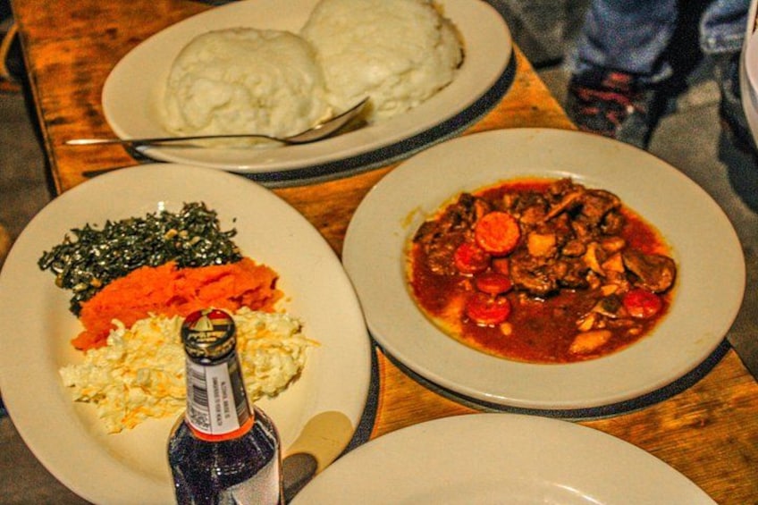 Three plates of food, one with a bottle of sauce, on a wooden table. 3