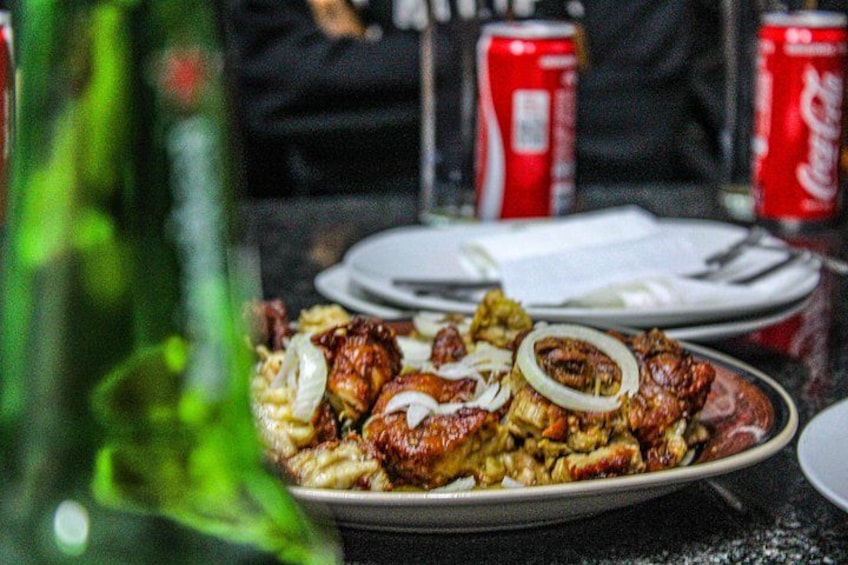 A meal with grilled meat and onions on a plate, with Coca-Cola cans in the background. 2