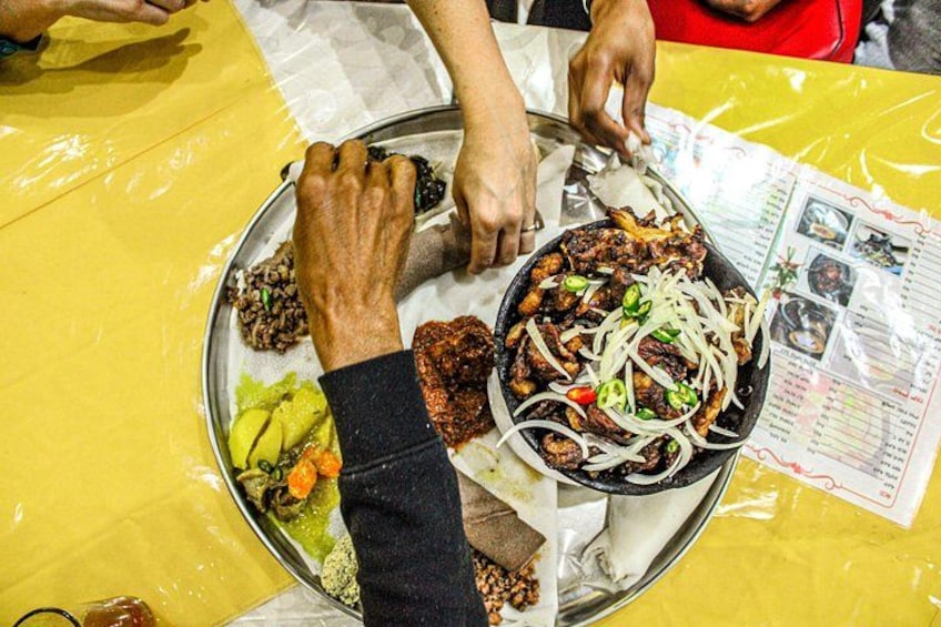 A person serving food from a metal tray onto a plate. 1