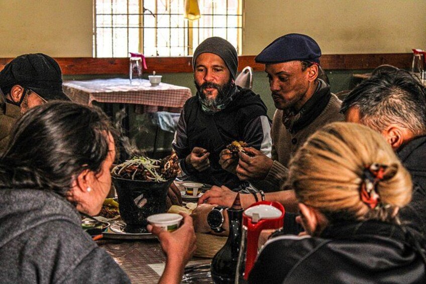 Un gruppo di persone sedute attorno a un tavolo, che mangiano e conversano in un ristorante. 2