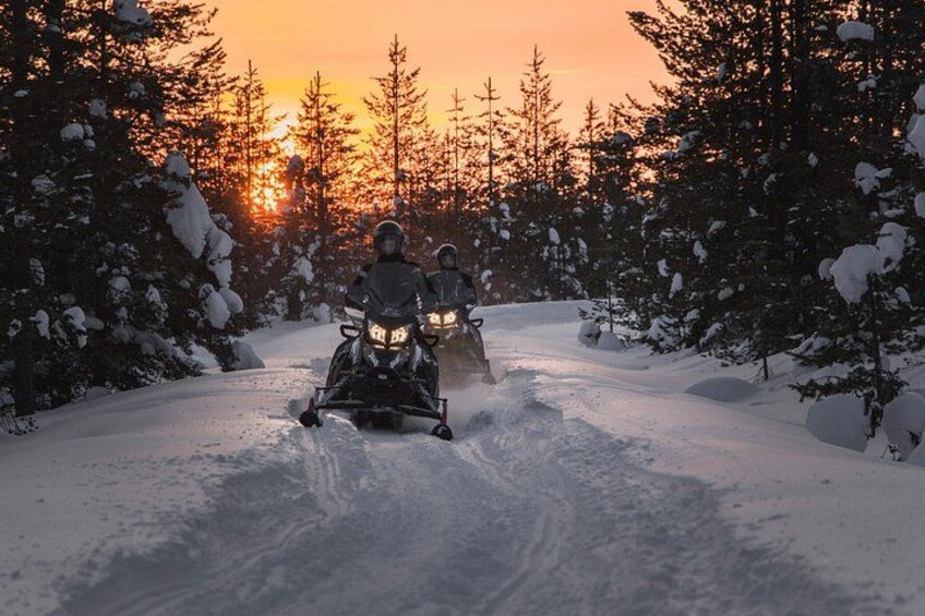 A snowmobile on a snowy path with a sunset in the background. 5