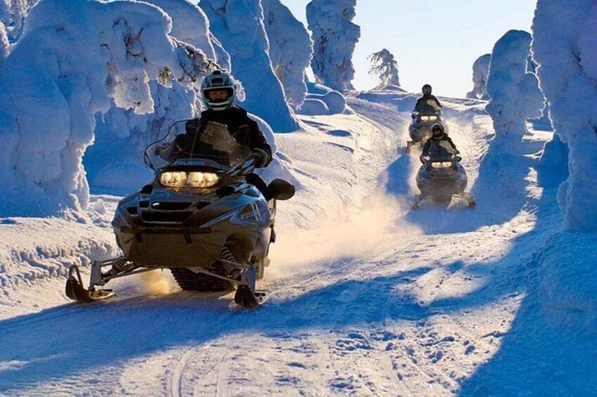 A snowmobile on a snowy trail with snowbanks on either side. 1
