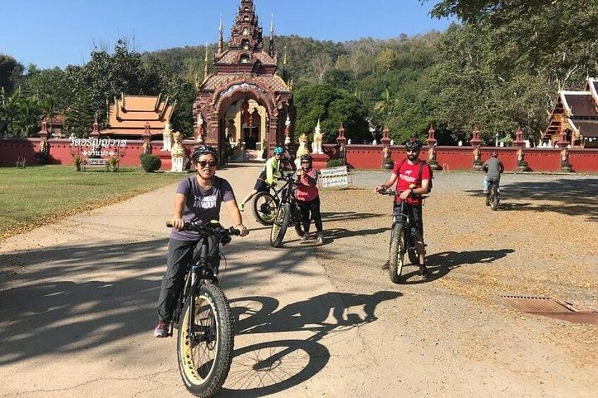 A group of people on bicycles in a park with a temple in the background. 4