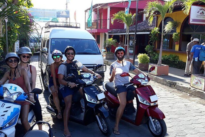 A group of people on scooters and a white van on a street with buildings and palm trees. 2