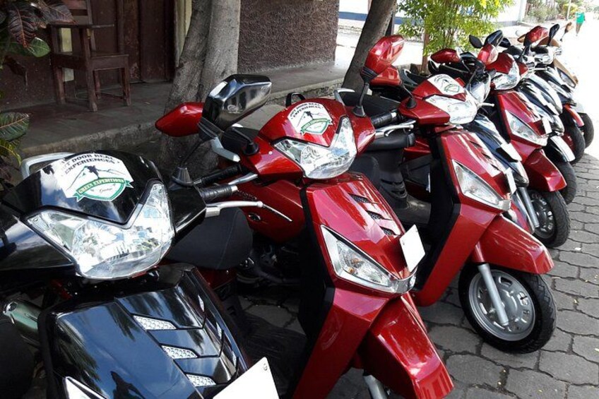 A row of red scooters parked on a paved surface. 1