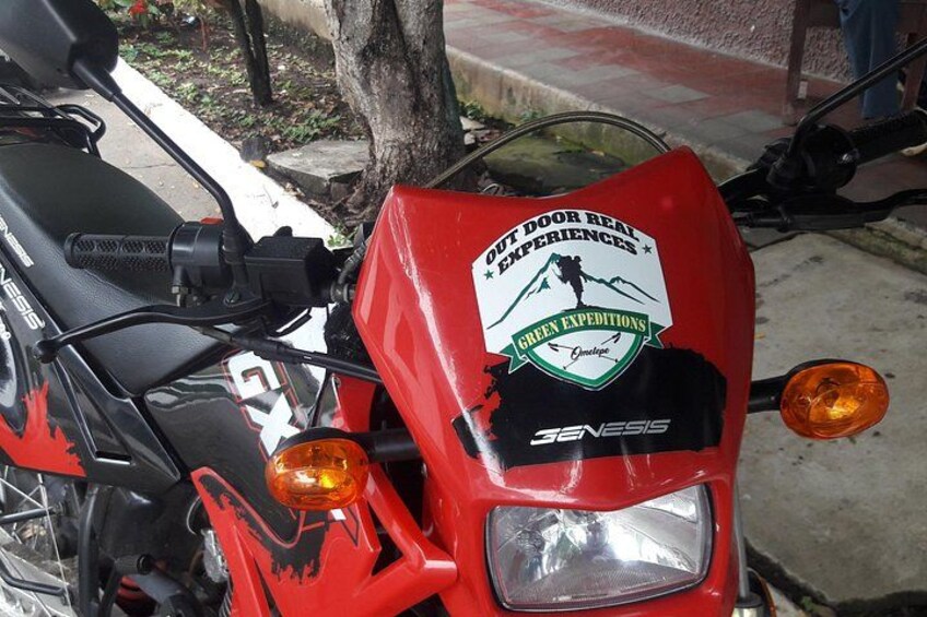 A red motorcycle with a sticker that reads 'OUT DOOR REAL EXPERIENCES GREEN EXPEDITIONS.' 4