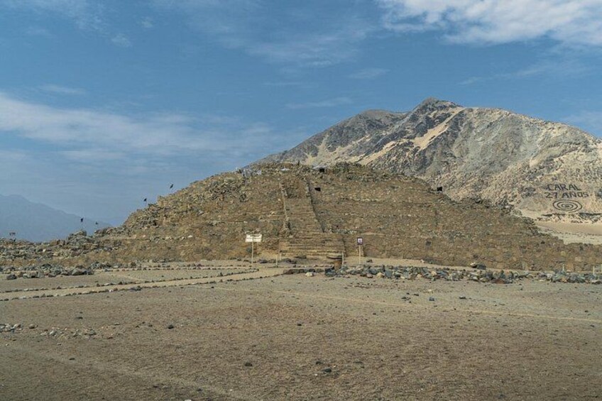 A mountainous landscape with a large rock formation and a sign that reads 'CARA 27 ANOS'. 5