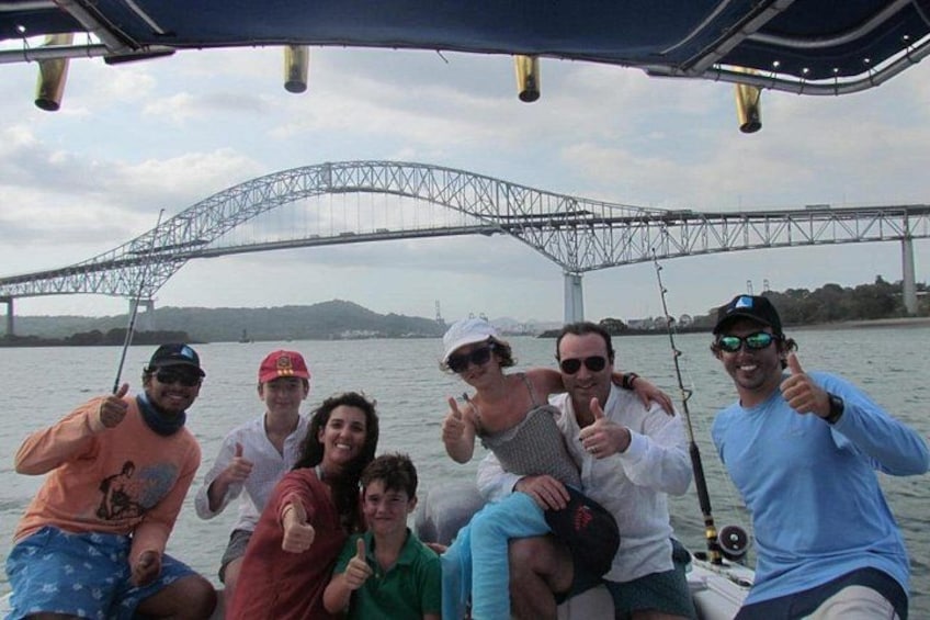 A group of people on a boat with a bridge in the background. 3