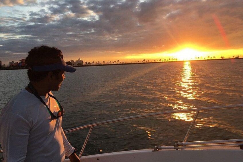 A person on a boat during sunset with a city skyline in the background. 2