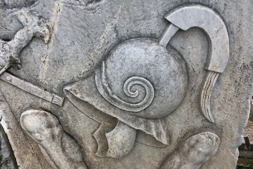 Een stenen sculptuur van een slak met een spiraalvormige schaal en een gebogen pijl. 5