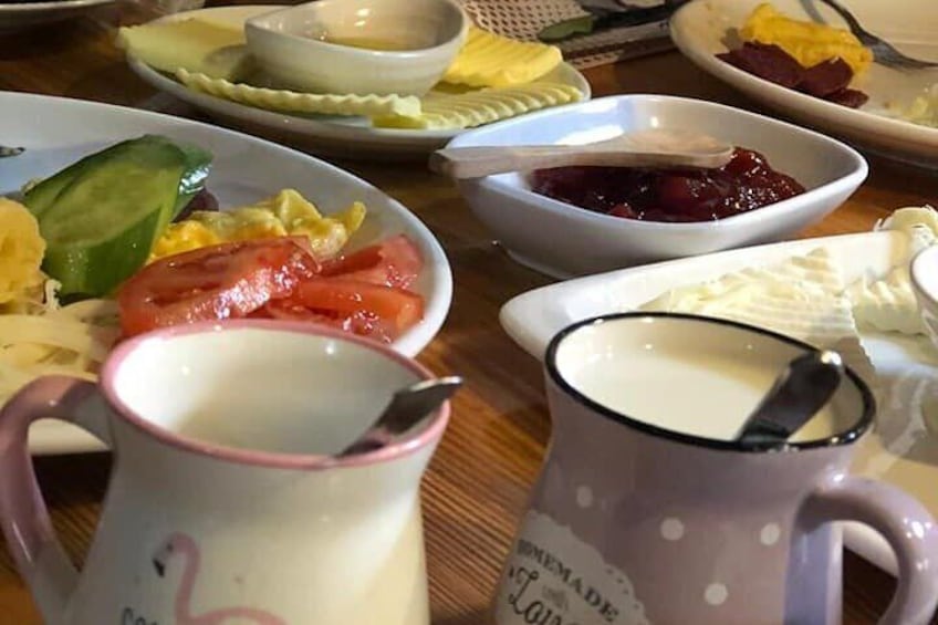 Una mesa con varios platos, incluyendo una jarra de leche, un bol de mermelada y fuentes con comida. 1