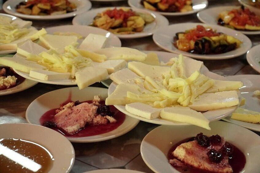 A variety of dishes including cheese, fruit, and a dessert with a berry sauce. 1