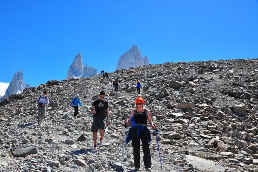 Hikers on a rocky mountain trail with a clear sky and distant peaks. 3