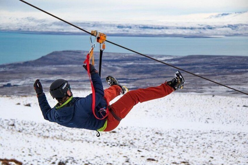 Une personne pratiquant le parachutisme, avec un parachute, un casque et un harnais, sur fond d’un paysage enneigé avec des montagnes et une étendue d’eau. 4