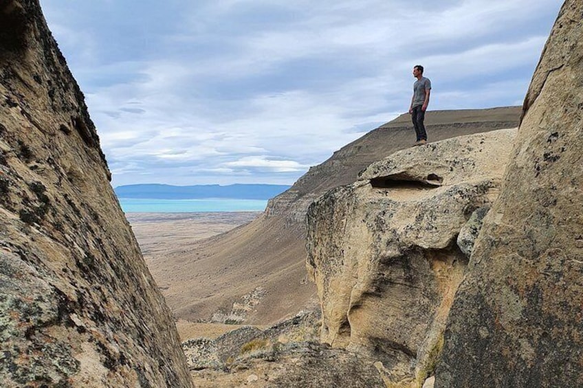 Une personne se tient debout sur un promontoire rocheux, surplombant un vaste paysage aride avec des montagnes lointaines. 5