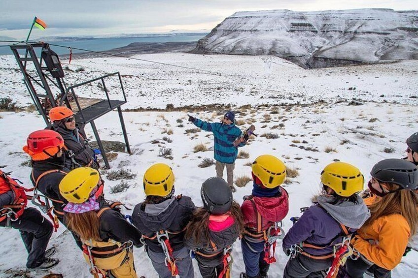 Un groupe de personnes, portant des casques et des harnais, se trouve sur une montagne enneigée, avec un guide qui se tient au centre. 3